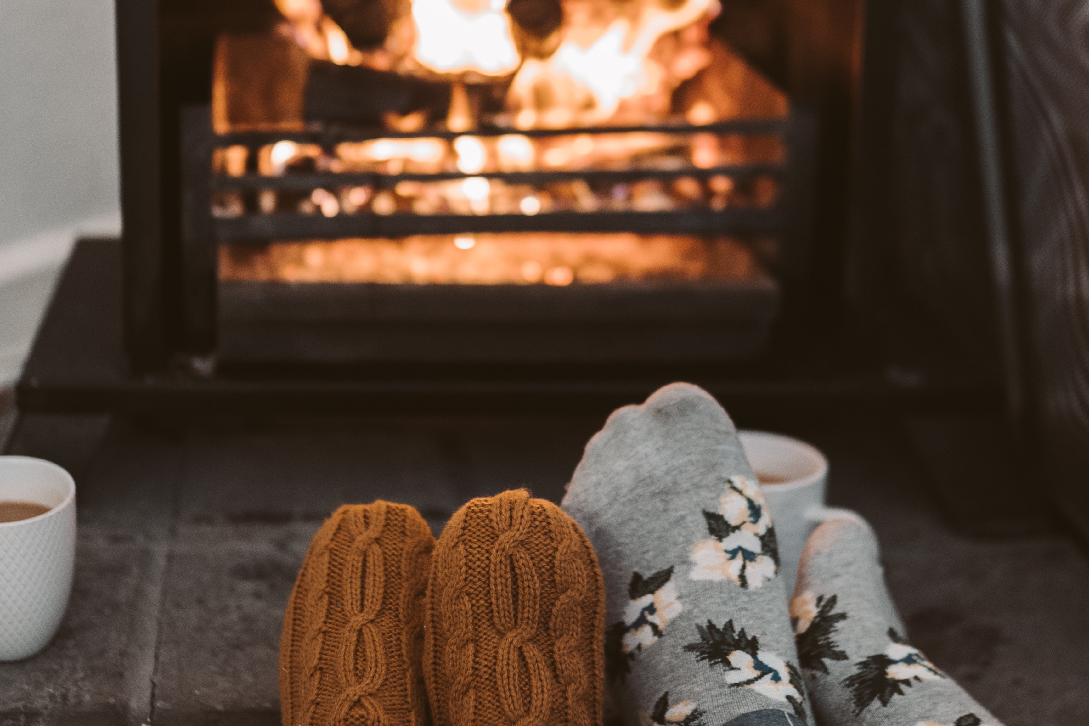 Picture of two pairs of feet in socks next to a fire.